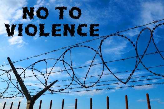 Barbed wire against the blue sky. The inscription in black stop violence. No to violence. The concept of freedom, human rights, imprisonment, restrictions, war, struggle and protest.