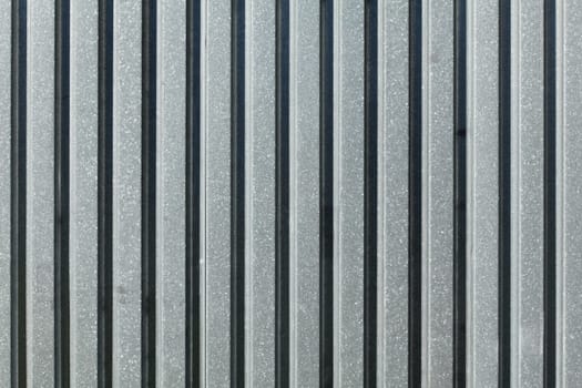 Metal plate fence, sun shining from side. Abstract construction background.