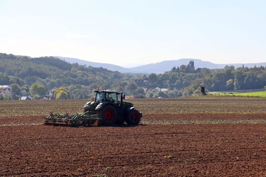 Landwirt eggt das Feld, im Hintergrund Burg Trendelburg, Hessen, Deutschland