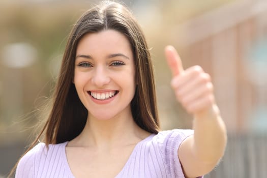 Happy teen gestures thumb up standing in the street