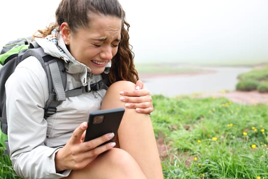 Hiker suffering knee ache asking for help on phone in the mountain