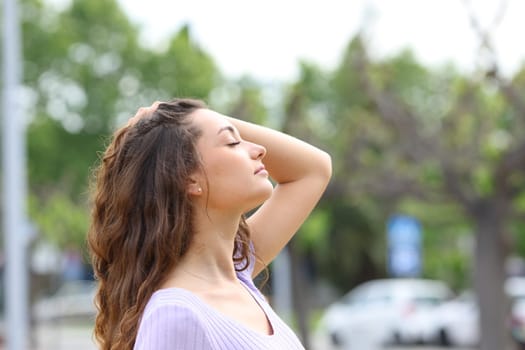 Profile of a woman breathing touching hair in the street
