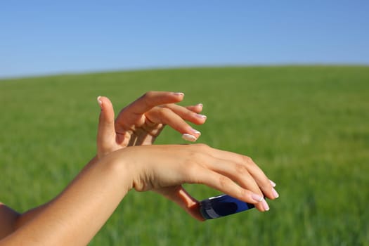 Close up of a woman hands hydrating skin applying moisturizer in a field