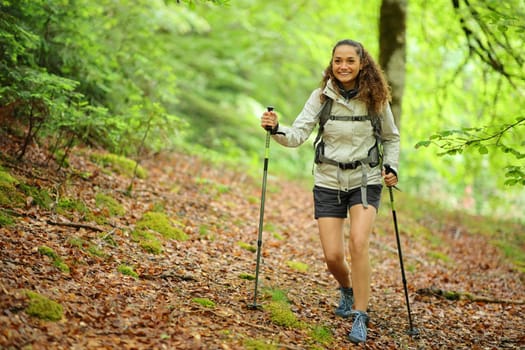 Front view portrait of a happy hiker walking in a forest