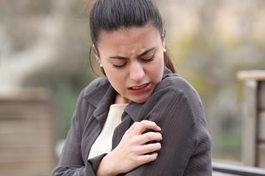 Stressed woman scratching itchy arm in a park