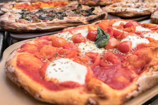 Italian pizza close-up. Close up of italian pizza on cutting board. Various pizzas in the shop window.