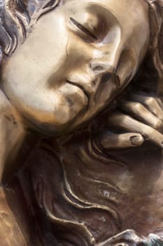 Vintage sculpture of sad woman in grief. Virgin Mary bronze statue. Religion, faith, suffering, death concept.