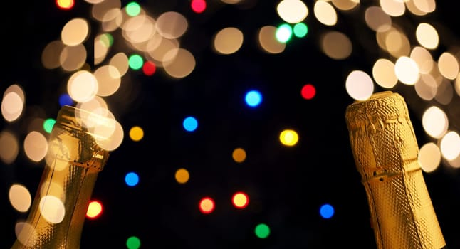 Two bottles of champagne on a colorful bokeh background with Christmas lights, New Year concept