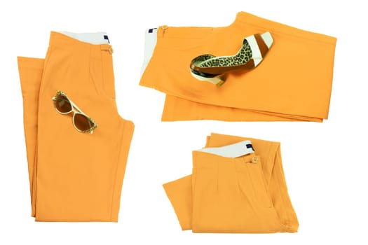 Collage woman clothes. Set of folded yellow elegant women trousers or denim pants with a matching of elegant single female high heeled shoe and sunglasses. Yellow fashion concept isolated.