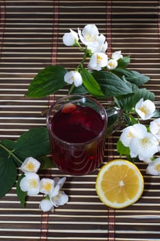 glass of red tea, nearby lemon and flower, subject drinks