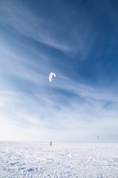 Kite surfer being pulled by his kite across the snow