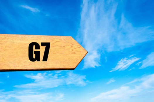 Wooden arrow sign pointing destination  G7 SUMMIT against clear blue sky with copy space available. Travel destination concept  image