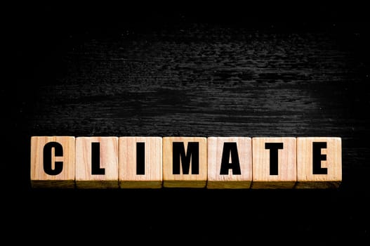 Word CLIMATE written on wooden small cubes with letters isolated on black background. Concept image with copy space available