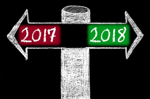 Opposite arrows with Year 2017 versus Year 2018. Hand drawing with chalk on blackboard. Choice conceptual image