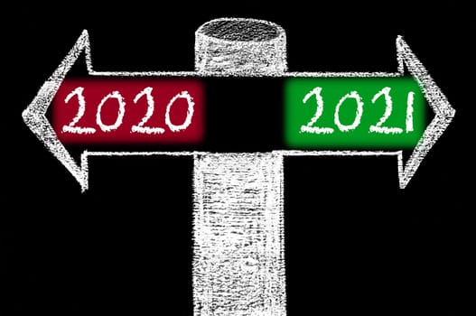 Opposite arrows with Year 2020 versus Year 2021. Hand drawing with chalk on blackboard. Choice conceptual image