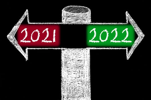 Opposite arrows with Year 2021 versus Year 2022. Hand drawing with chalk on blackboard. Choice conceptual image