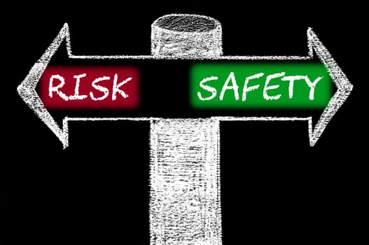 Opposite arrows with Risk versus Safety. Hand drawing with chalk on blackboard. Choice conceptual image