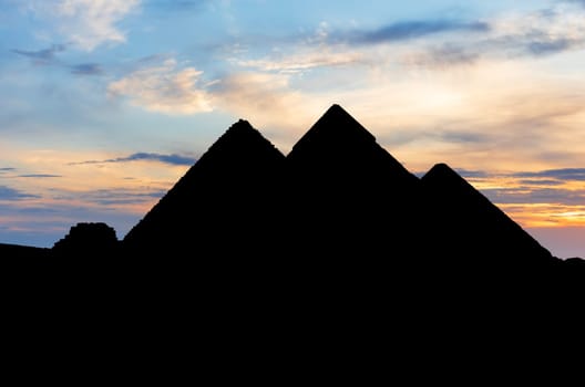The pyramids in the dark, silhouettes at sunset, Giza, Egypt.