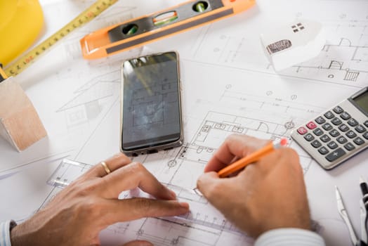 Architect workplace. Architectural building design and construction plans with blueprints paper project plans, designing man edit building or architecture online check by smart mobile phone screen