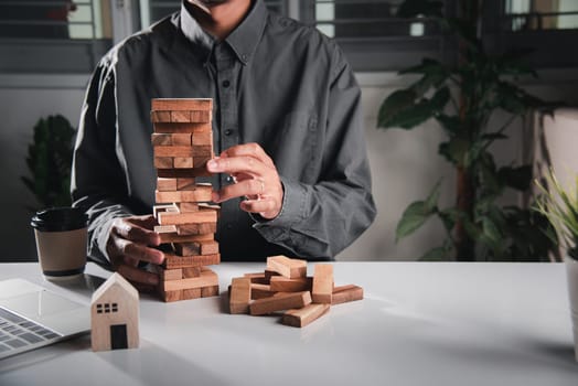 Alternative risk plan. Business hand playing tower wooden blocks game, man pull one wood block from tower he clenched his fist, show great joy in accomplishing it, Business gambling growth concept