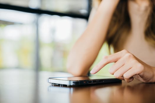 Beautiful Asian female has transfer money financial internet banking on mobile phone, young woman using smart phone for shopping online at cafe coffee shop near windows in the morning