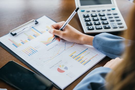 Woman accountant writing on business paper marketing statistic and data, Asian businesswoman working with paperwork charts and graphs and calculator, summary report planner, accounting concept
