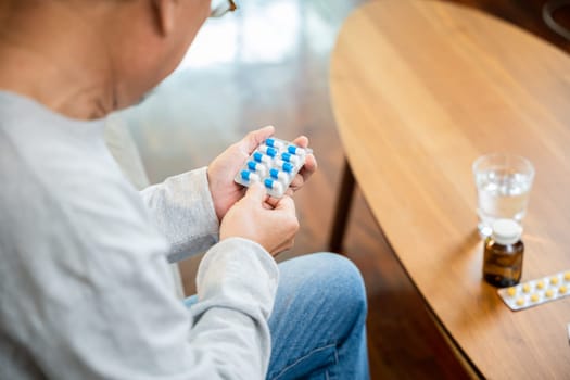 Asian worried senior man with medicine pills he read on see how to take pills before taking, old man buy herbal self cure Rx pill online from pharmacy, home isolation, Medical service concept