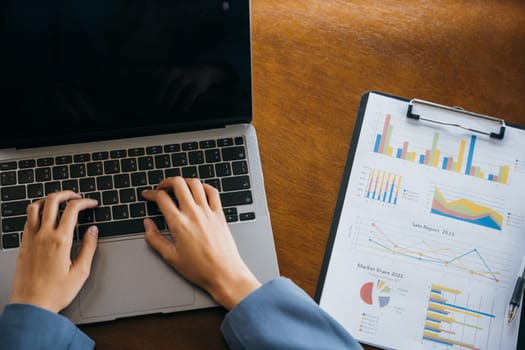 Professional business woman working on laptop computer with chart graphs and calculator on desk in office, top view business woman checking and analysing report, Accountant calculate financial report