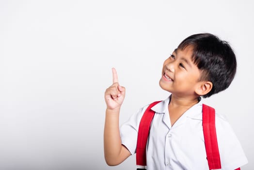 Asian toddler smiling happy wear student thai uniform red pants keeps pointing finger at copy space in studio shot isolated on white background, Portrait little children boy preschool, Back to school