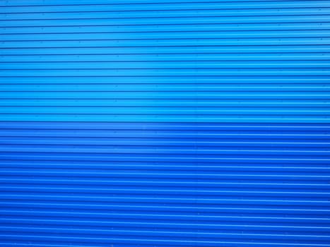 Profiled sheet. Facing wall or roofing building material used in construction in the construction of external fences, walls and roofs. Corrugated blue metal background with gradient.