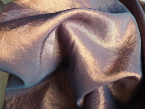 Beautiful fabric - taffeta, gently folded in waves. Crumpled material that looks like silk or brocade. Overflow and color gradient at different lighting angles. Fabric for sewing clothes and curtains.