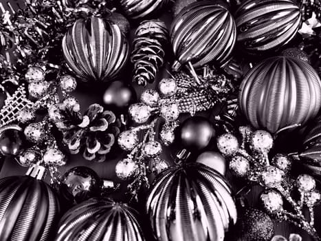 Christmas background with Christmas decorations, holiday balls, bells, bows, fir cone, Christmas tinsel. Happy New Year and Merry Christmas. Black and white monochrome photo with lilac filter