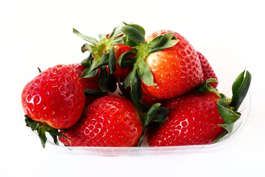 Ripe strawberries in a plastic package on a white background. Delicious fresh berries in a container for sale to customers. Keeping food fresh. Healthy food, vitamins and microelements