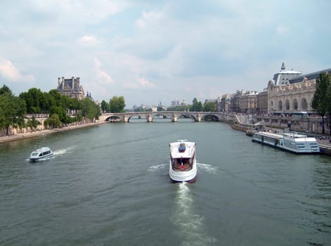 Paris, France, May 20, 2022 Embankment of the River Seine. A pleasure boat sails down the river. On both banks there are ancient buildings. Tourist attractions of Paris in the summer afternoon. Cloud