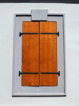 Window with old wooden shutters. Metal curly braces. White wall. Country style. Petrovaradin, Novi Sad, Serbia. Vintage retro architecture building facade