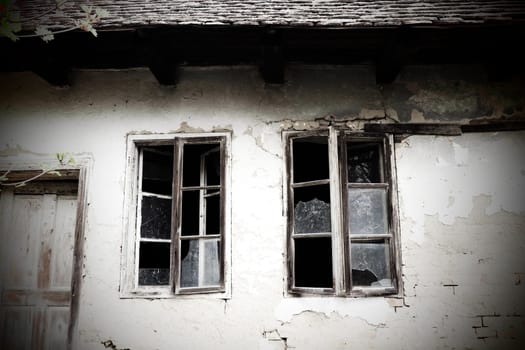Abandoned spooky old house. Wooden windows and doors. The hut is a mud hut. Samani house. White stucco plaster. Halloween theme. Aging, loneliness, departure, war and devastation. Ukraine, Donbass.