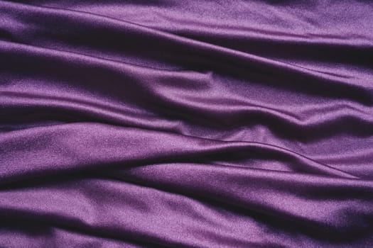 Velour fabric, similar to silk. Textiles in a folds and beautiful waves. Purple, pink, magenta shades on the drapery. Sewing material for evening dresses, furniture upholstery, curtains and interior