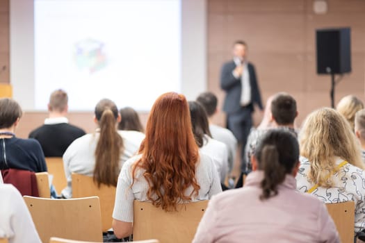 Speaker giving a talk in conference hall at business event. Rear view of unrecognizable people in audience at the conference hall. Business and entrepreneurship concept