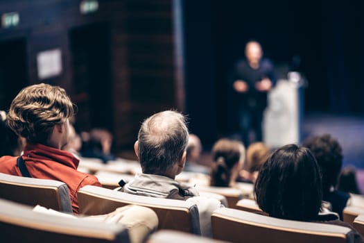 Speaker giving a talk in conference hall at business event. Rear view of unrecognizable people in audience at the conference hall. Business and entrepreneurship concept