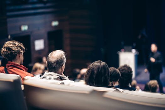 Speaker giving a talk in conference hall at business event. Rear view of unrecognizable people in audience at the conference hall. Business and entrepreneurship concept