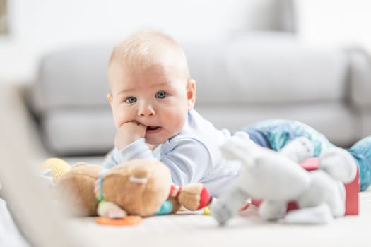 Cute baby boy playing with hanging toys arch on mat at home Baby activity and play center for early infant development. Baby playing at home.