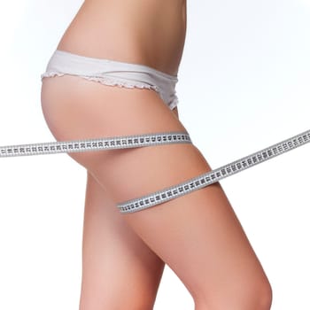 Woman measuring her thigh using a tape measure, isolated on white background