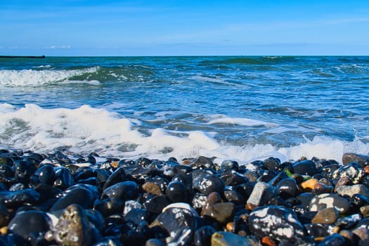 on the beach of the baltic sea with many stones. in addition waves rolling on the beach. Nature landscape shot