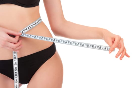 Slender woman measuring her waist with metric tape measure after a diet, isolated on white background
