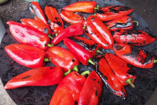 Roasting red peppers for a smoky flavor and quick peeling. Thermal processing of the pepper crop on metal circle. Brazier container used to burn charcoal fuel for cooking, heating or cultural rituals
