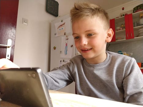 Sremska Mitrovica, Serbia, May 20, 2020 Blond boy with laptop. The child looks at the monitor. The emotion of joy.