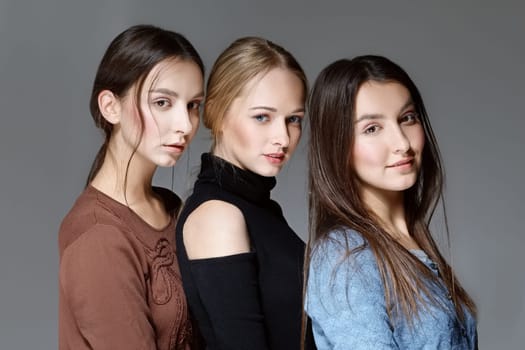Three cheerful girls in casual clothes posing and expressing emotions