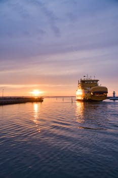 Ferry leaving harbor to Visingsoe island on Vaettern lake for sunset. Lighthouse in the background. Landscape shot from Scandinavia