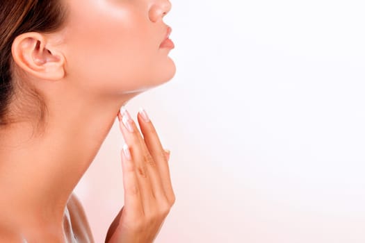 Pretty woman touches her neck against an abstract background with blurred lights.