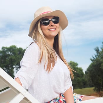 The attractive blond hair smiling woman in sunhat and sunglasses is enjoying in summer vacation.